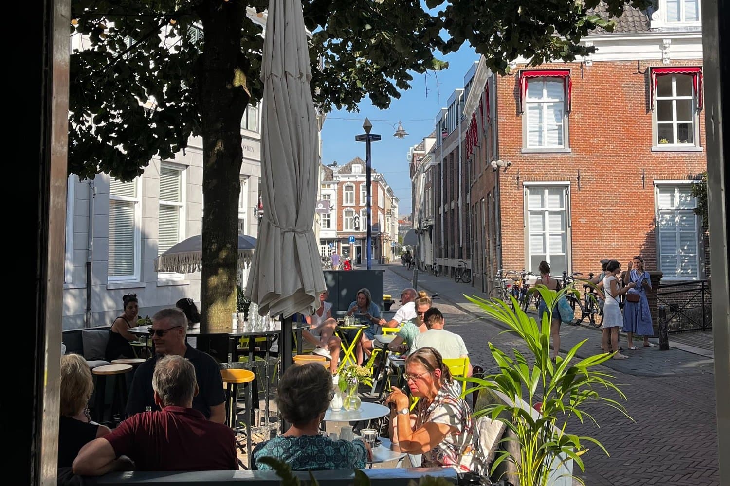 Vanuit de zaak door de open deuren naar het zonnige terras en de straat richting het centrum.